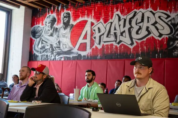 Sales development reps at their desks under the A Players mural