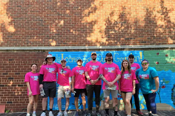 A volunteer crew in front of a painted mural wall