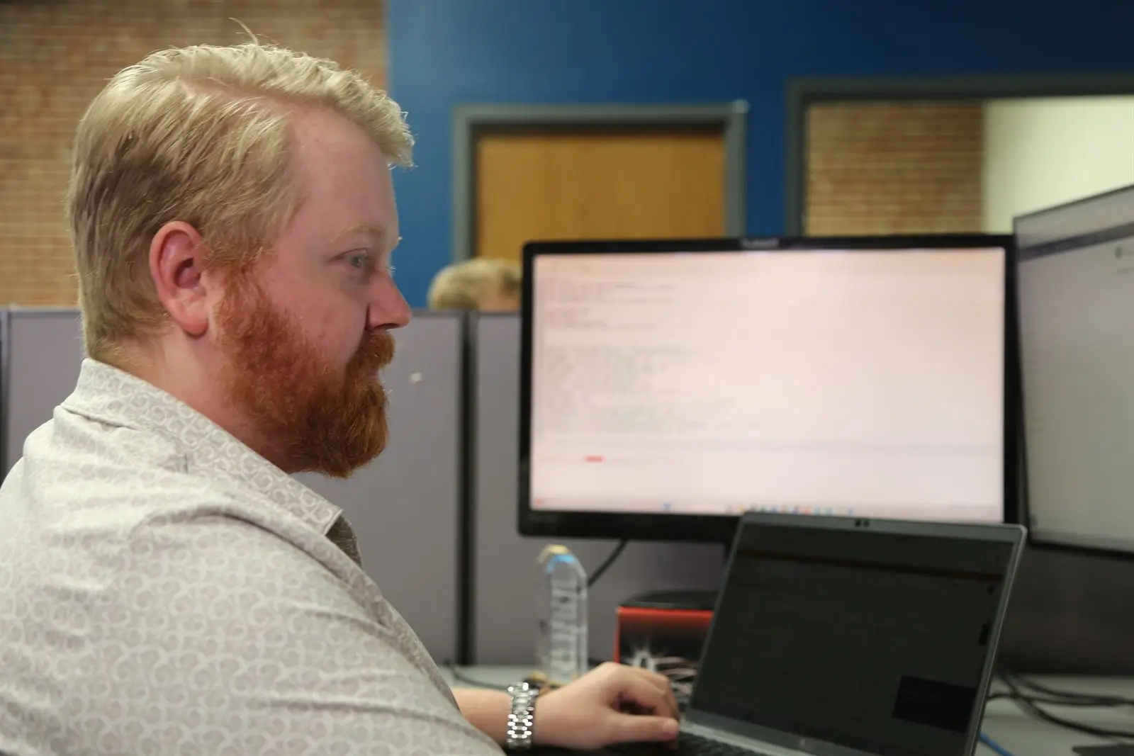 A team member working at a dual-monitor desk