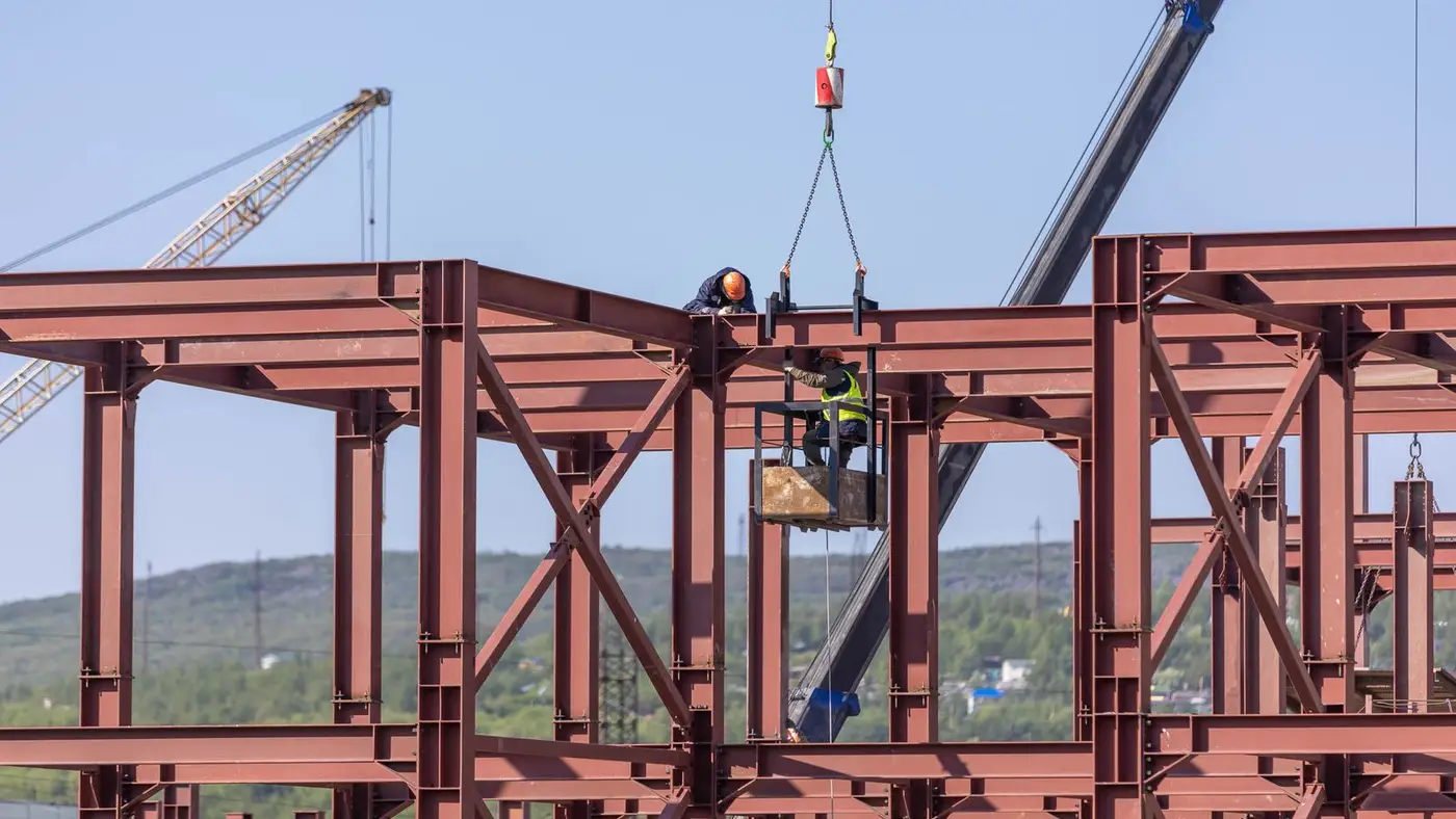 Ironworkers setting a steel frame with cranes