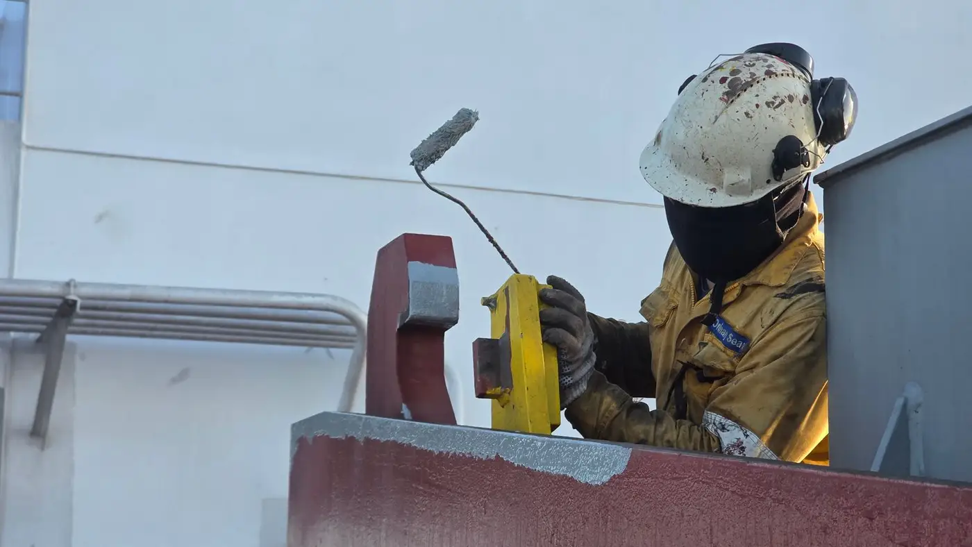 Painter in protective gear coating an industrial structure
