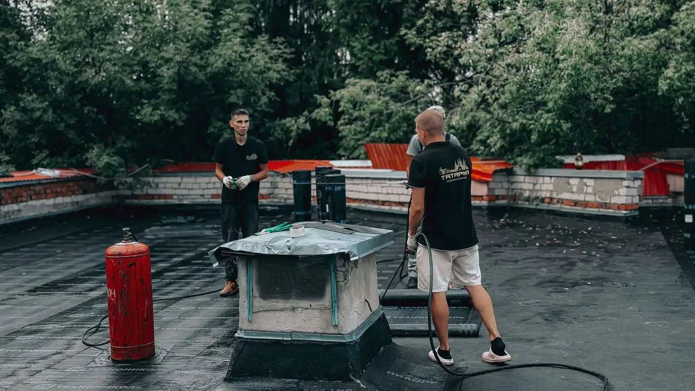 Two roofers working on a flat commercial roof